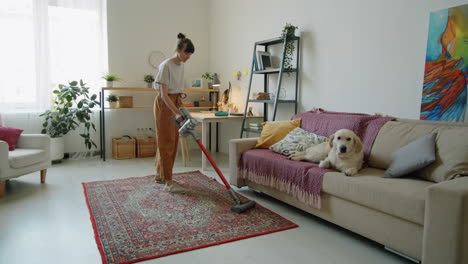 Woman-Vacuuming-Home-while-Dog-Lying-on-Sofa